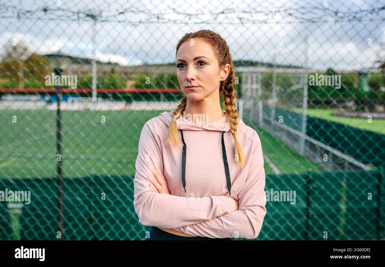 Donna sportiva seria con trecce di pugili in posa con braccia incrociate Foto Stock