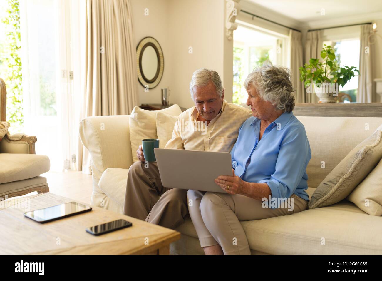 Coppia caucasica senior seduta sul divano utilizzando un computer portatile Foto Stock