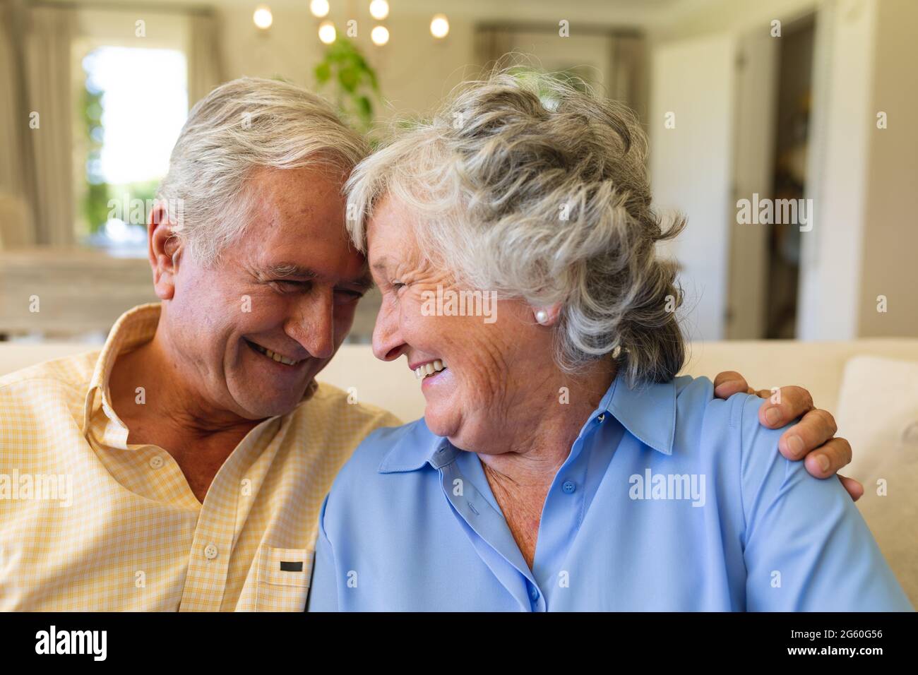 Coppia caucasica senior seduta sul divano abbracciando e sorridendo Foto Stock