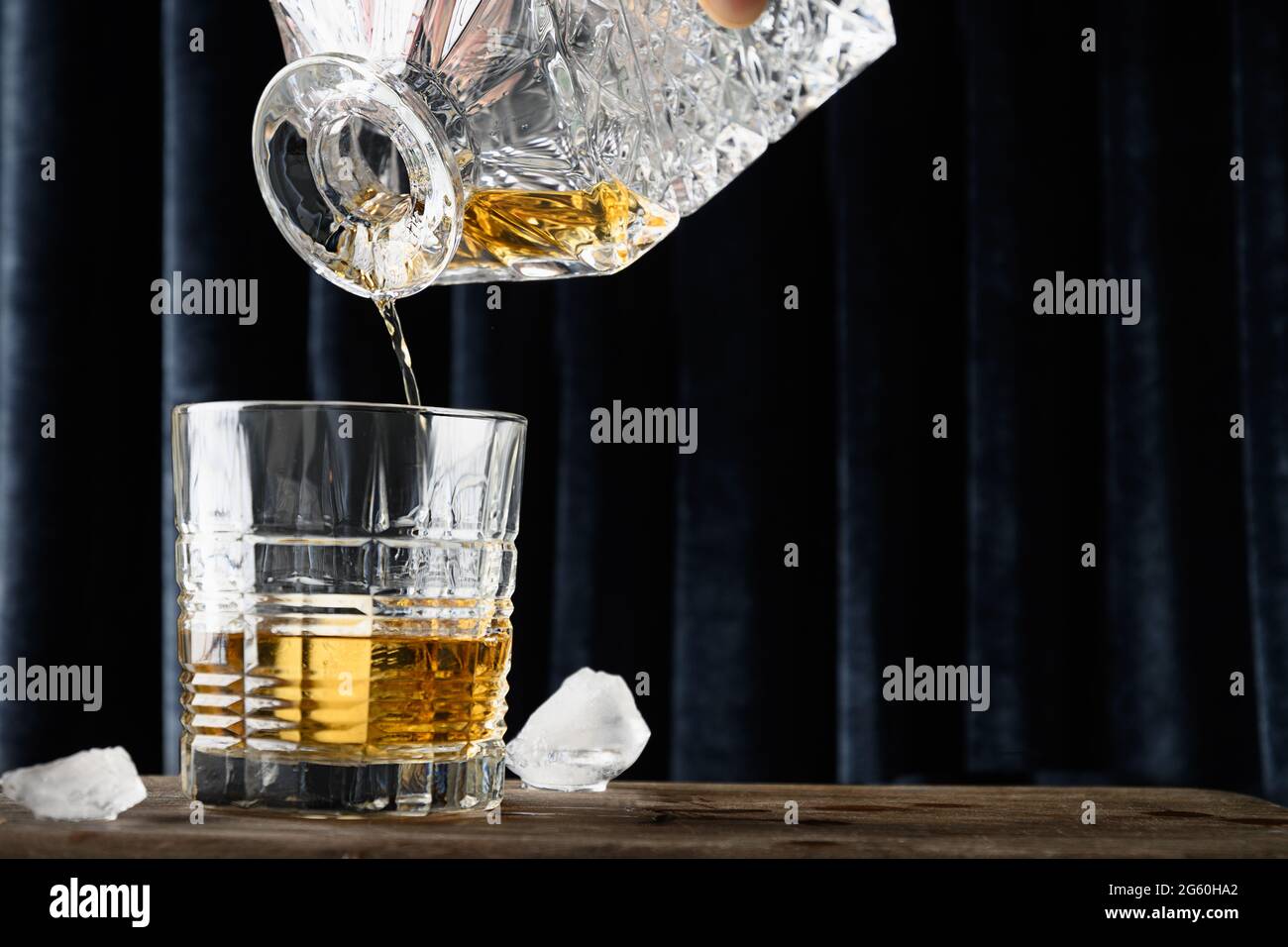 Versando whiskey freddo in rocce su fondo tenda blu scuro. Primo piano. Foto Stock