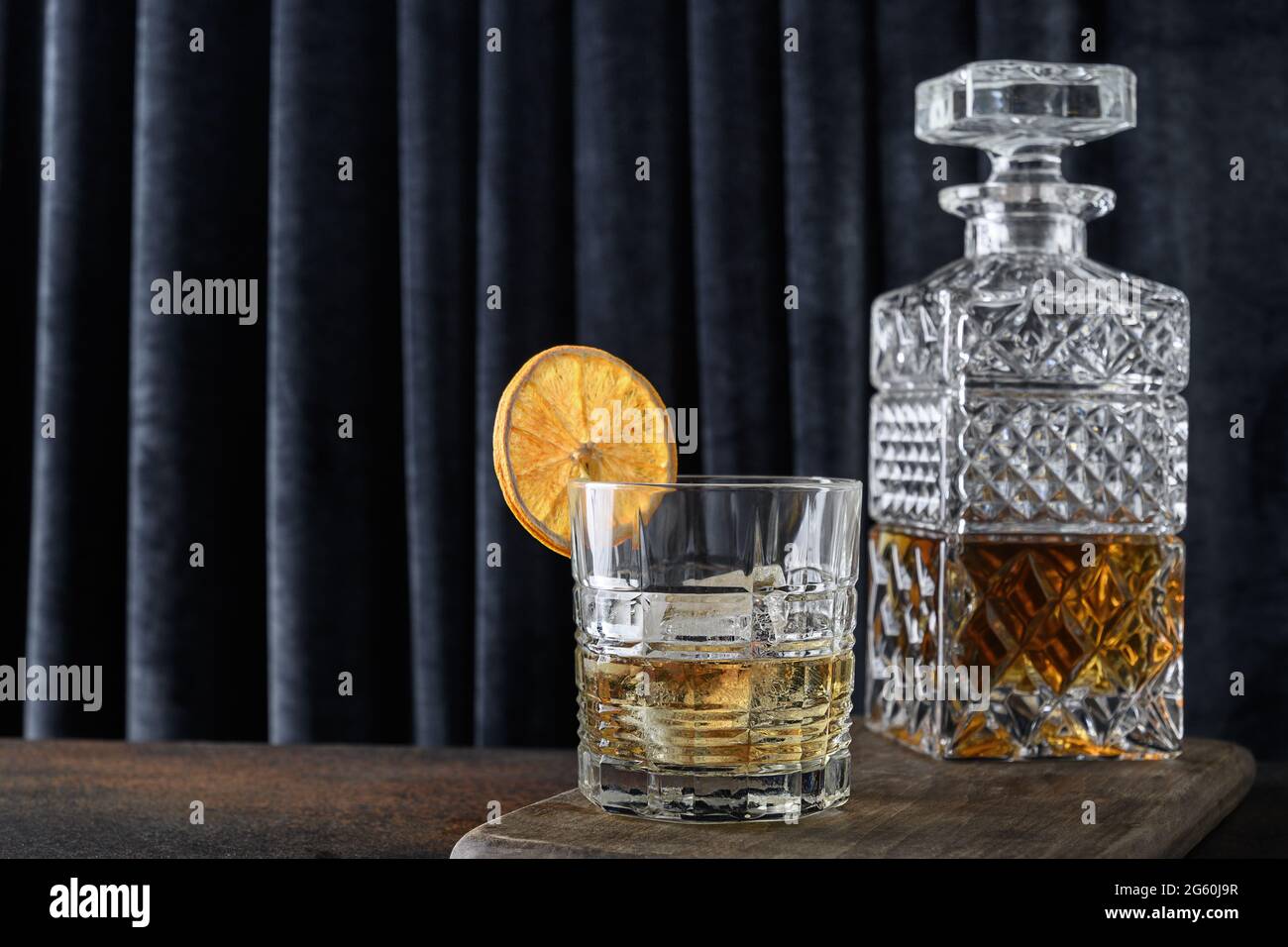 Il whisky freddo guarnire una fetta di arancia su uno sfondo blu a tenda. Spazio di copia. Foto Stock