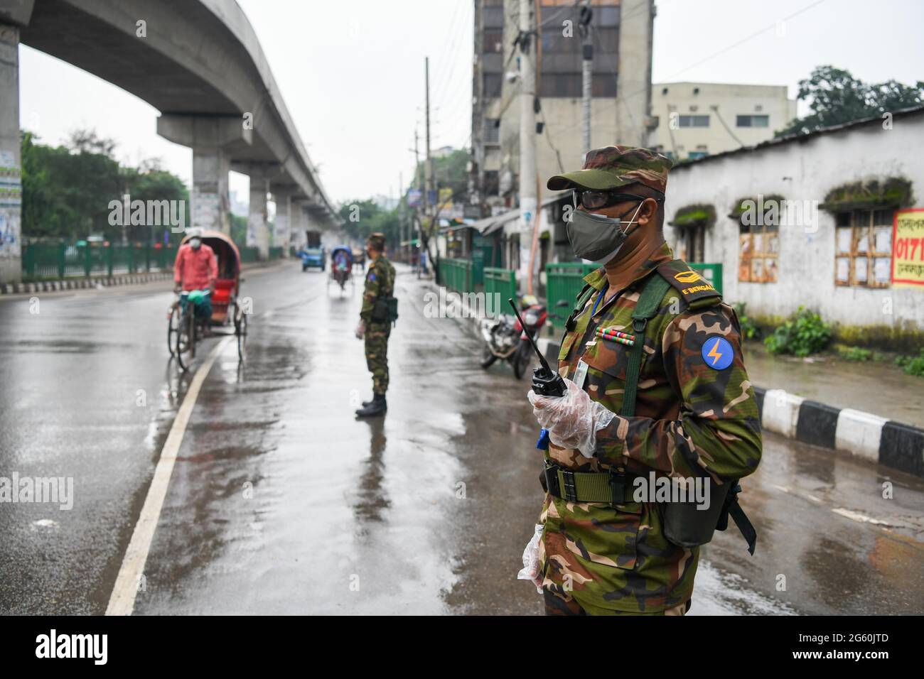 L'esercito del Bangladesh che indossa maschere e guanti si trova in guardia lungo la strada come parte di una misura per arginare la diffusione della pandemia del coronavirus.il governo del Bangladesh ha annunciato un nuovo blocco per contenere la diffusione del coronavirus Covid-19 in Bangladesh. Foto Stock