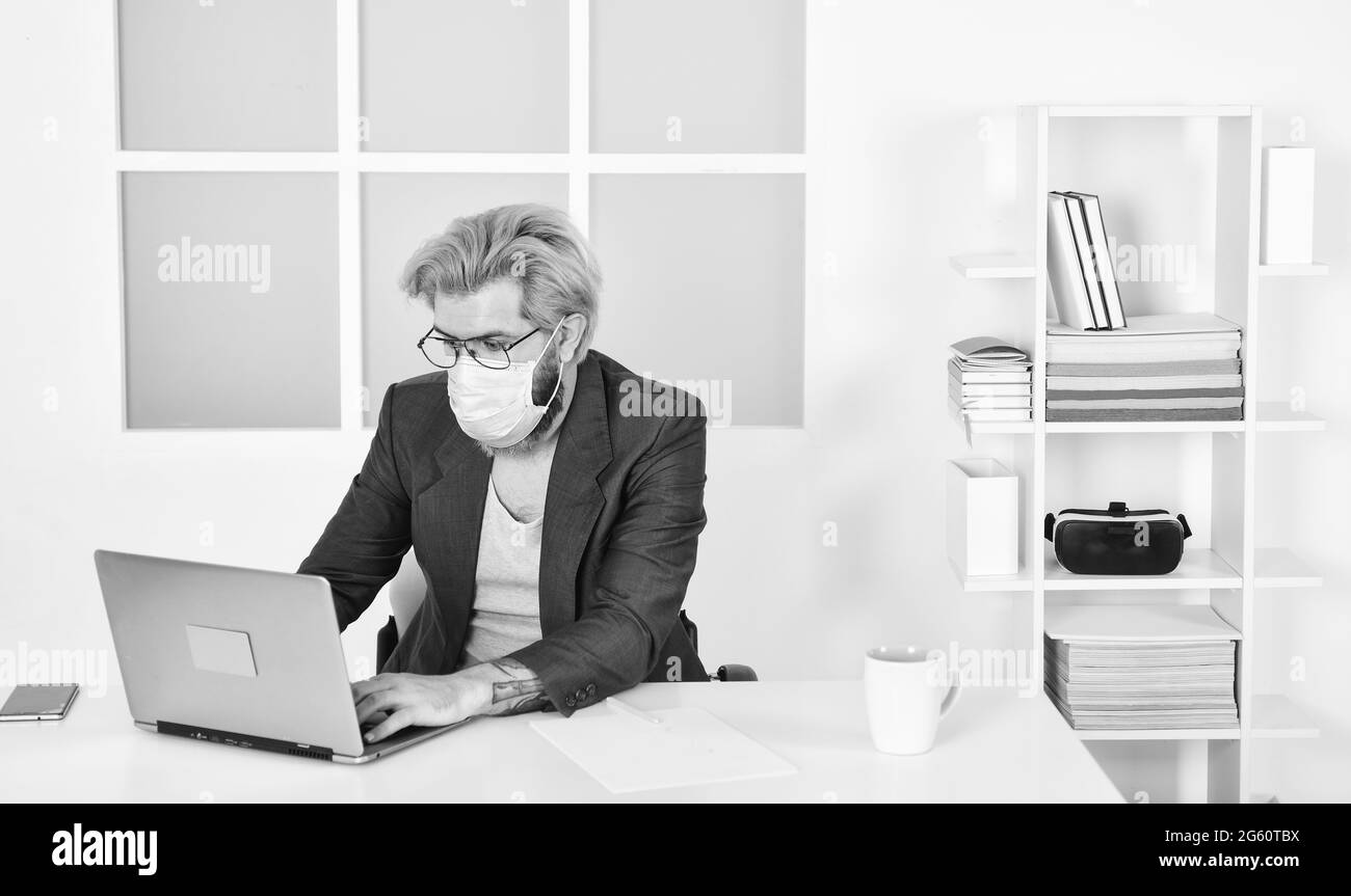 Tattica di auto-isolamento top Response per la gestione dello scoppio di COVID 19. Ufficio domestico. Uomo indossare maschera medica lavoro con computer portatile. Evitare il contatto con altri Foto Stock