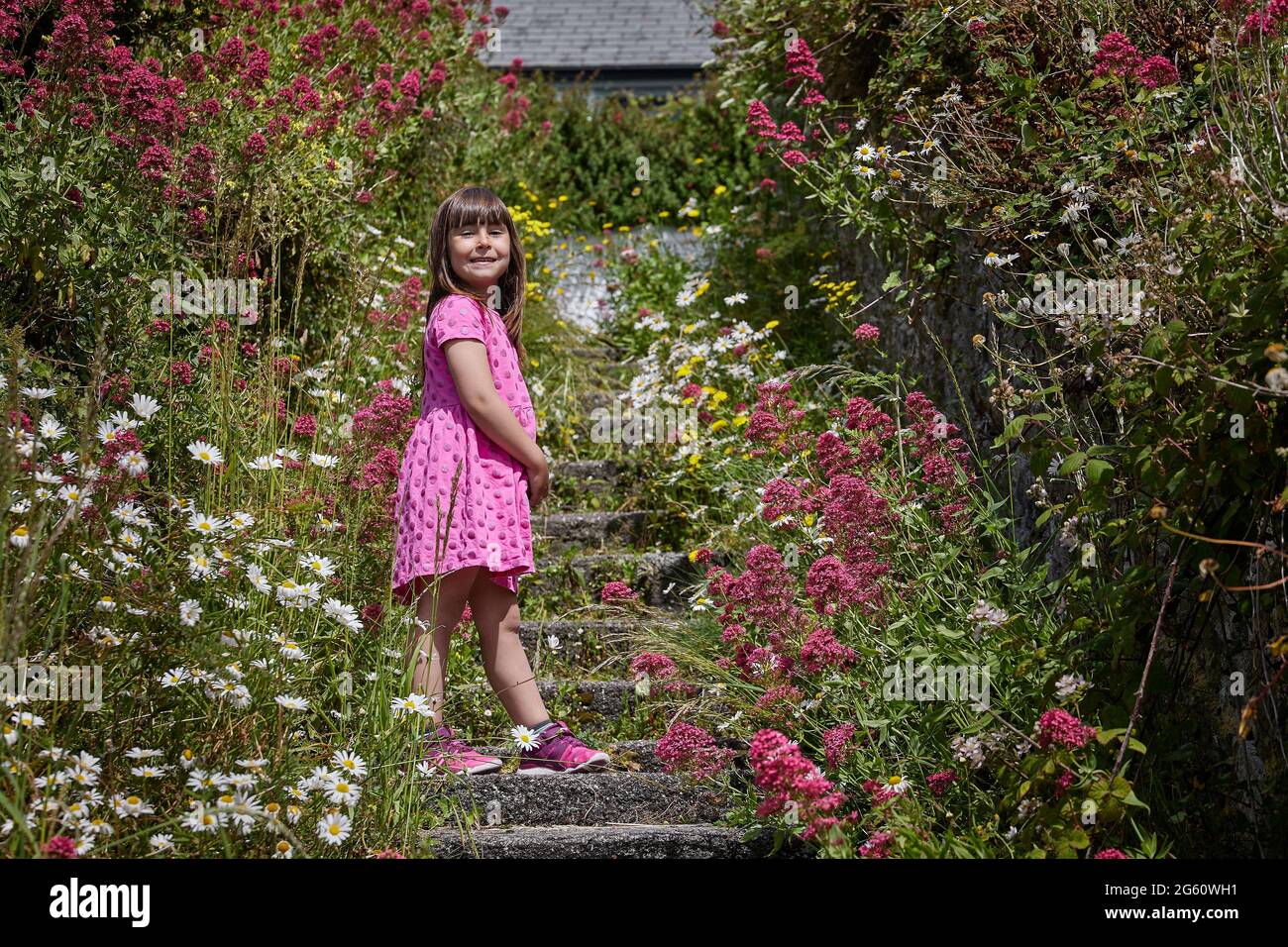 Caucasica ragazza circondata da fiori, estate o primavera immagine Foto Stock