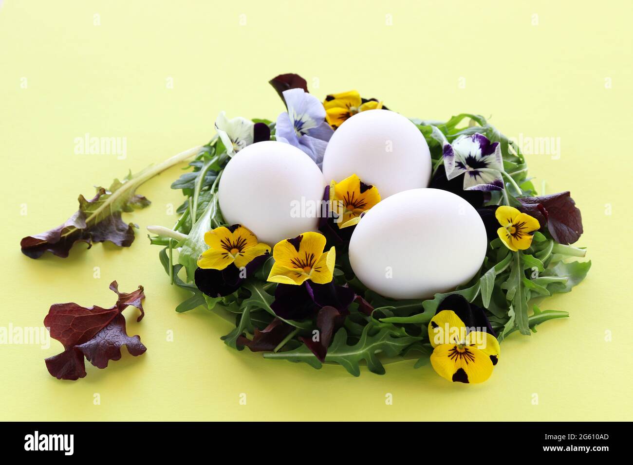 Nido d'uovo fatto da foglie di insalata e fiori. Decorazione di Pasqua. Primo piano. Foto Stock