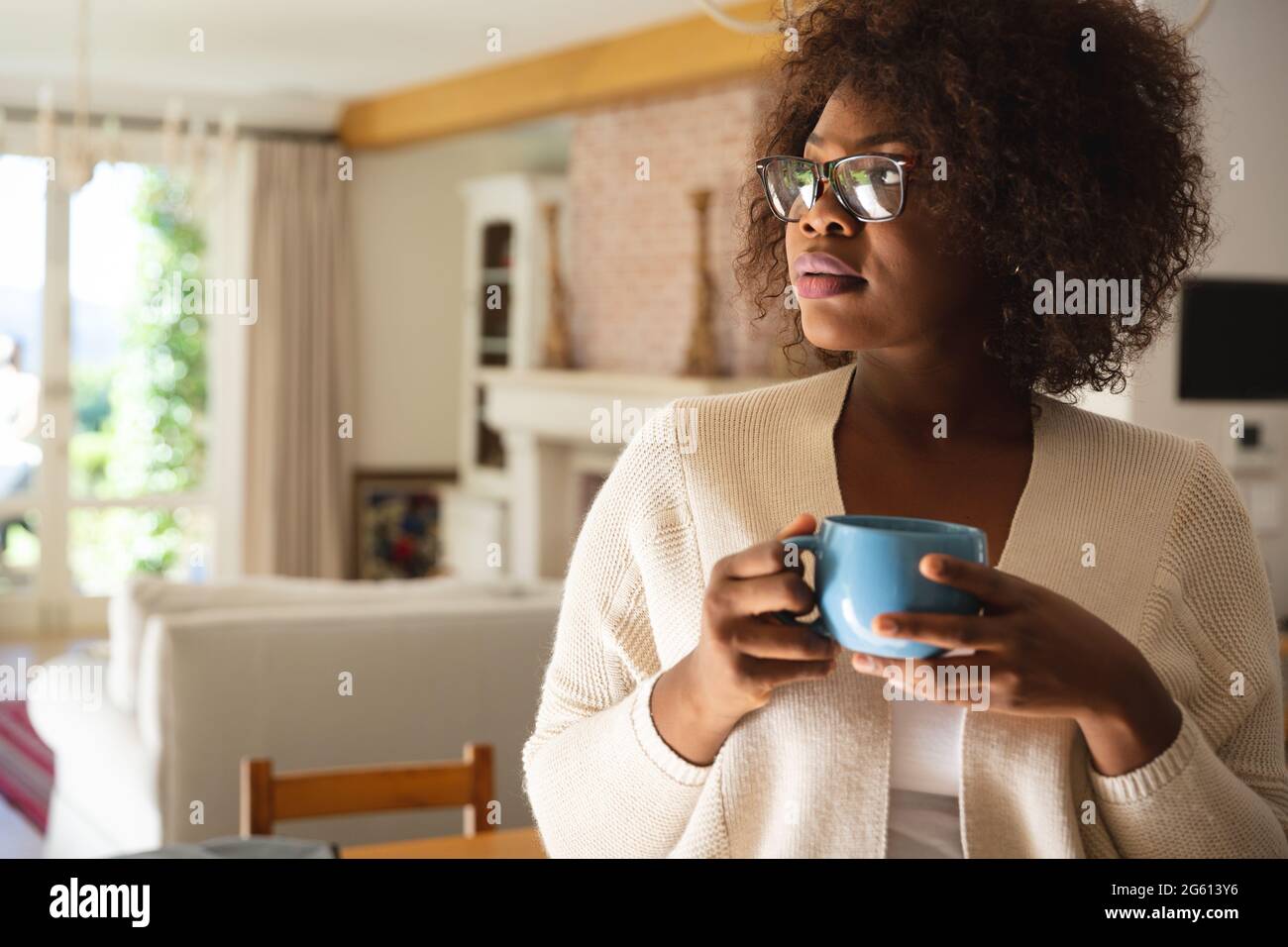 Donna afro-americana premurosa in piedi in sala da pranzo con una tazza di caffè Foto Stock