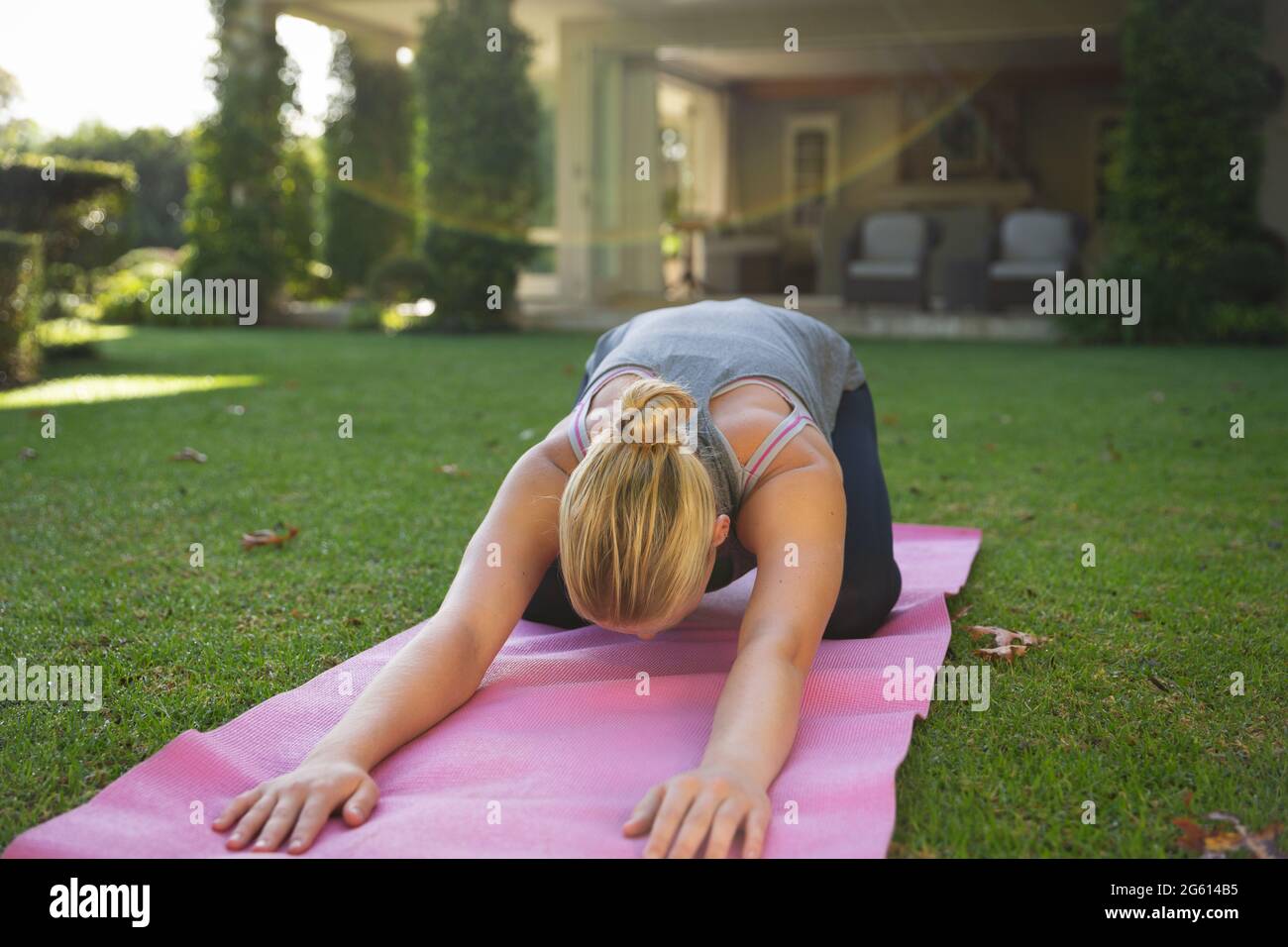Donna caucasica che pratica yoga in giardino, inginocchiarsi e stretching Foto Stock