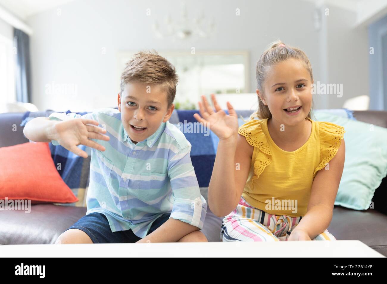 Fratello caucasico e sorella sventolando e sorridendo durante la videochat a casa Foto Stock