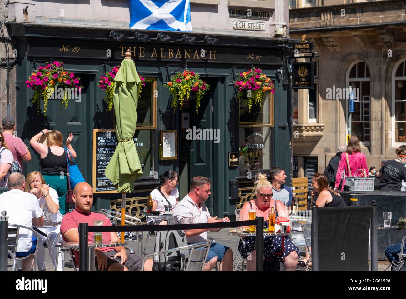Edimburgo, Scozia, Regno Unito. 1 luglio 2021. Le temperature calde e il sole hanno attratto molti membri del pubblico nei caffè e nei bar all'aperto di Edimburgo e nel nuovo centro commerciale St James Quarter, inaugurato la scorsa settimana. PIC; i bevitori godono del sole all'Albanach sul Royal Mile. Iain Masterton/Alamy Live News Foto Stock