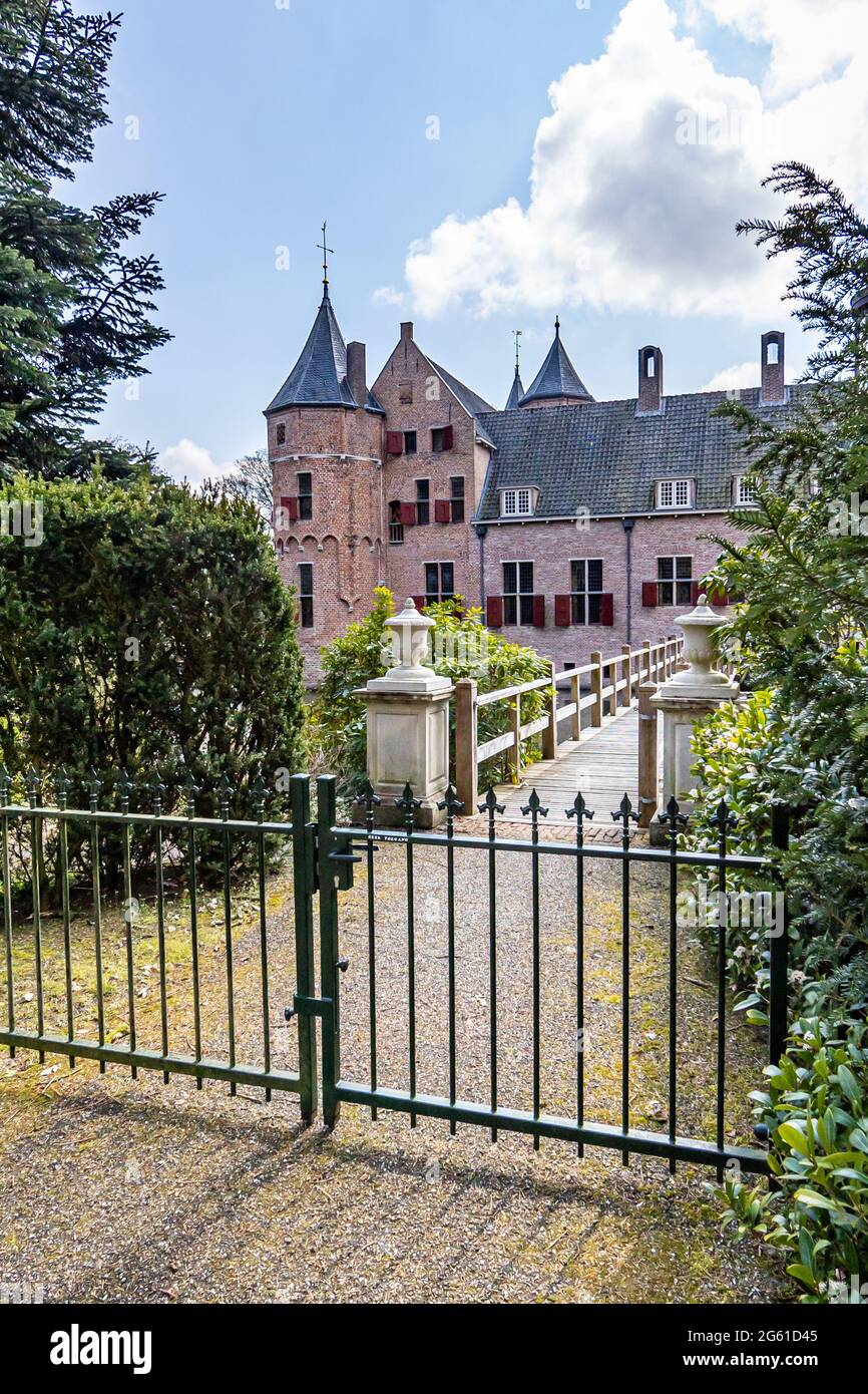 Porta del fabbro, ponte di legno al castello di Het Oude Loo circondato da vegetazione verde, soleggiata giornata di primavera con cielo blu e nuvole bianche in Paleispark KR Foto Stock