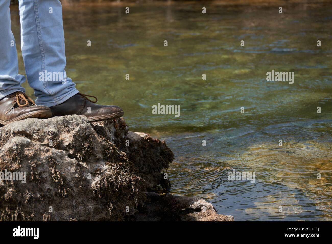 Vista ad angolo basso dell'uomo in piedi sulla scogliera rocciosa, concetto di viaggio Foto Stock