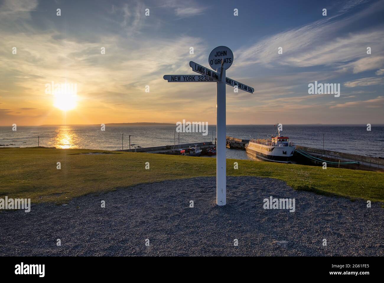 Il sole tramonta dietro l'iconico cartello di John o'Groats nelle Highlands scozzesi, Regno Unito Foto Stock
