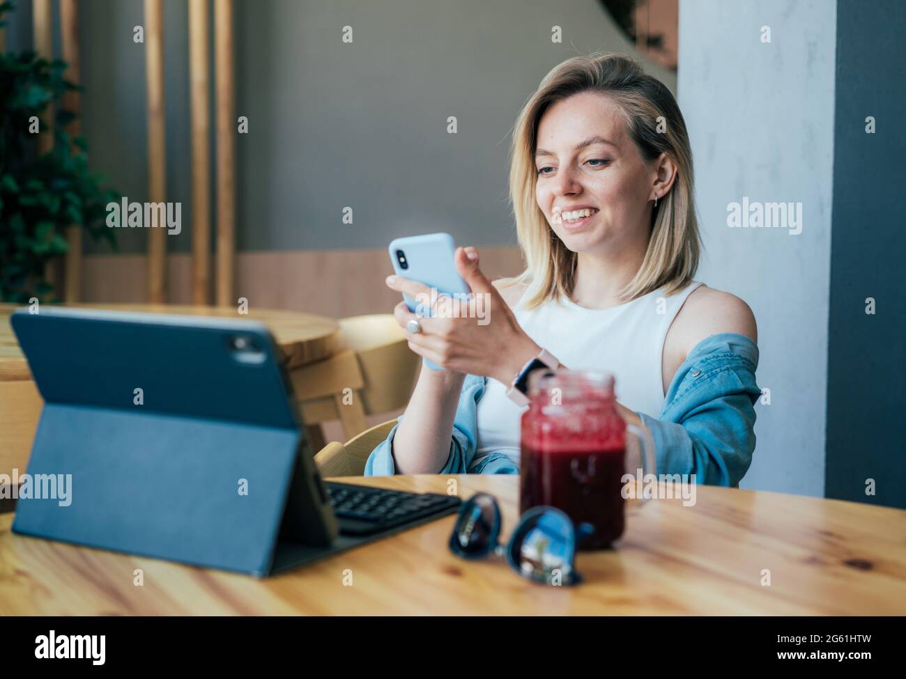 Felice rilassata giovane donna che chiacchiera al telefono mentre si siede in un bar. Ragazza d'affari che ha fatto colazione in un caffè mentre lavora su Internet. Foto Stock