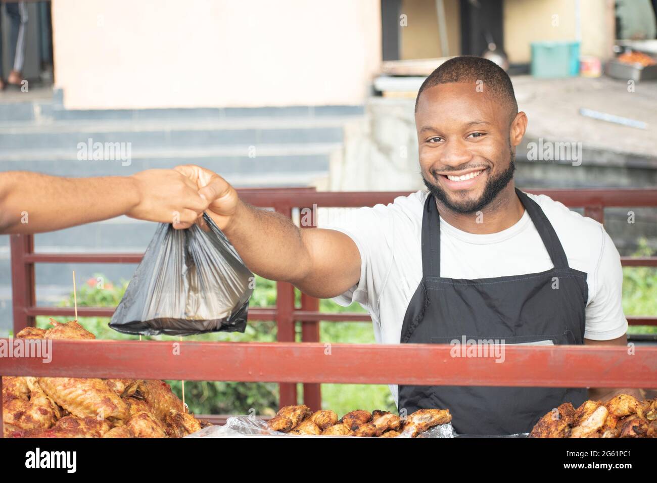 uomo africano che serve pollo alla griglia da take out Foto Stock