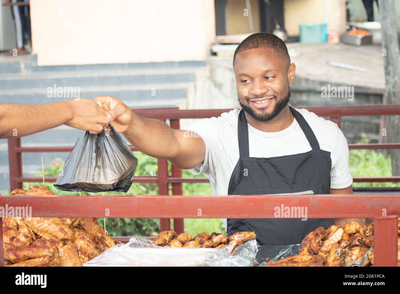 uomo africano che serve pollo alla griglia da take out Foto Stock