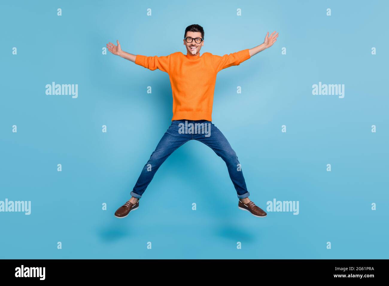 Foto a lunghezza intera di persona allegra che salta in alto divertirsi fare figura stella isolato su sfondo blu Foto Stock