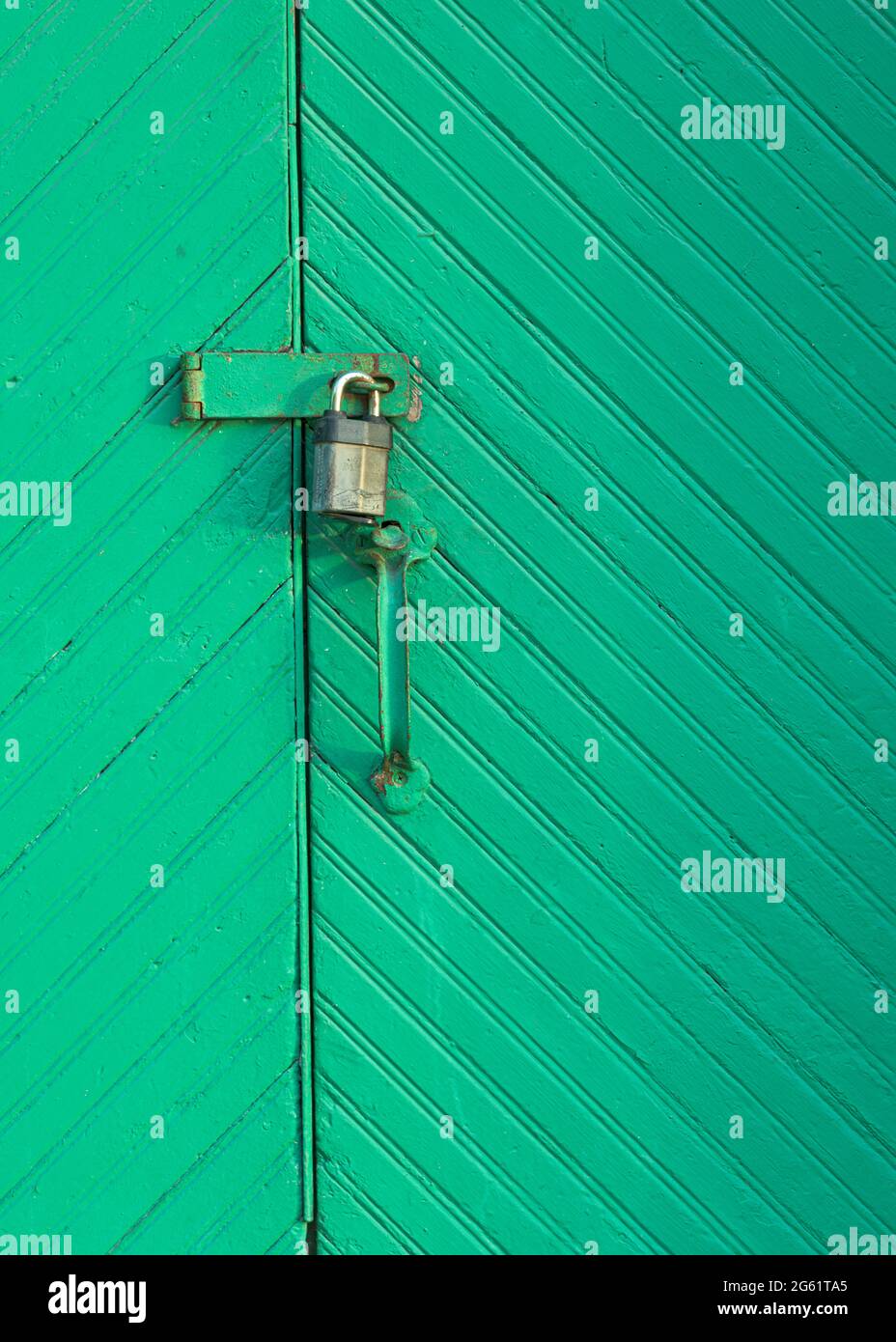 Esterno chiuso vecchie porte in legno verde con lucchetto pensile Foto Stock