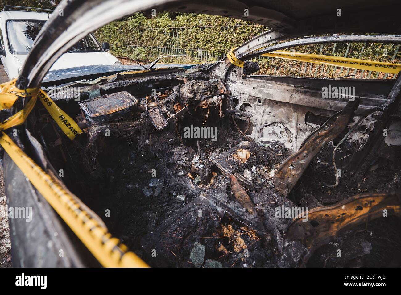 Londra | UK - 2021.06.12: Interno di un abbandonato, rubato bruciato fuori auto blu parcheggiata sul marciapiede spotб legato con giallo non attraversare striscia Foto Stock