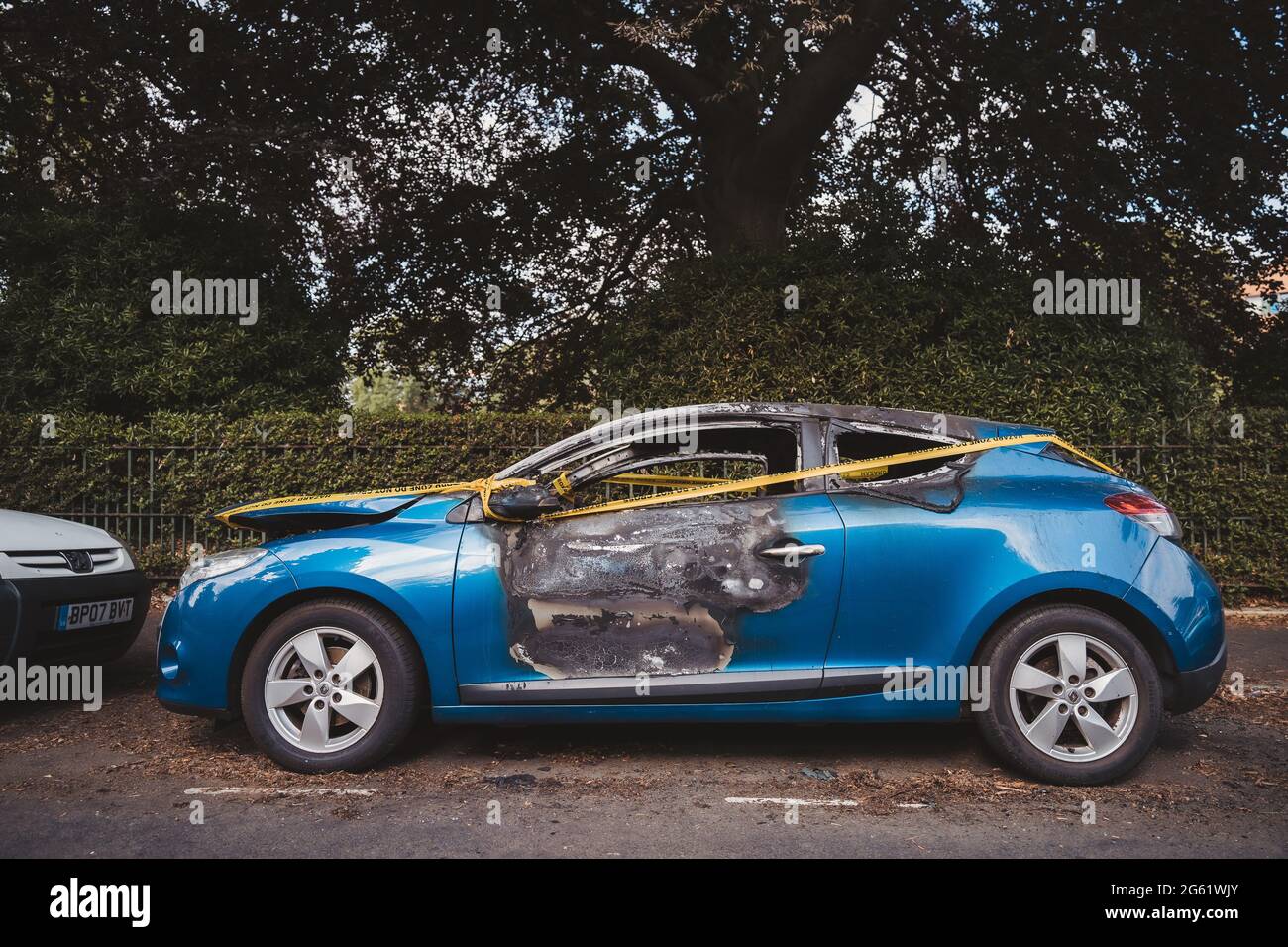 Londra | UK - 2021.06.12: Un'auto blu abbandonata, rubata bruciata parcheggiata sul parcheggio laterale spotб legata con la striscia gialla non attraversare Foto Stock