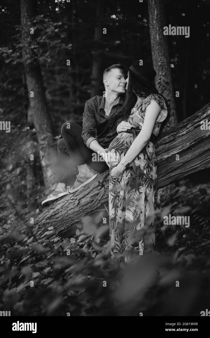 Futuro papà e mamma. Foto in bianco e nero di una giovane famiglia romantica felice nella foresta in estate. Donna incinta in attesa di un bambino, abbracciando con suo marito Foto Stock