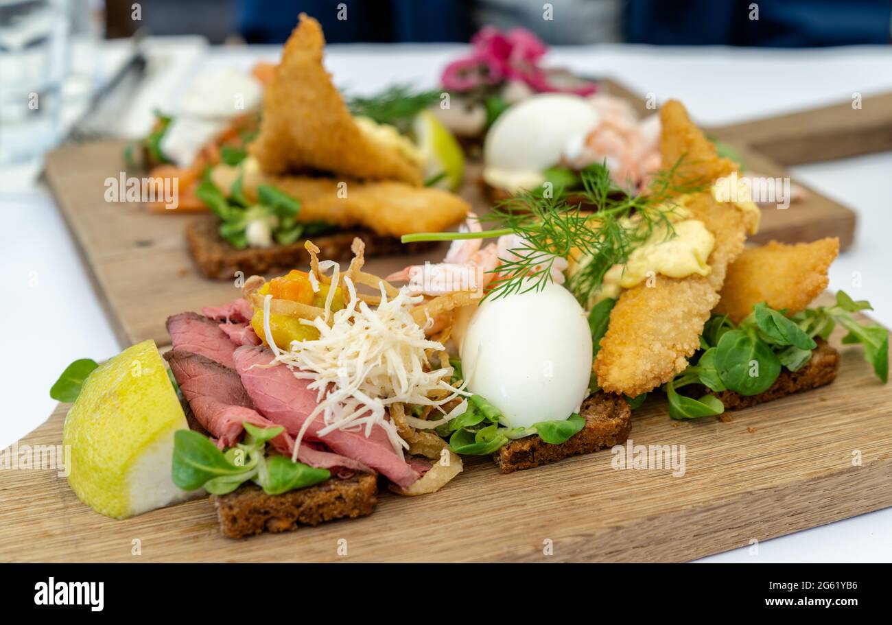 Una vista ravvicinata dei deliziosi panini Smørebrød su un piatto di legno come una tipica colazione scandinava Foto Stock
