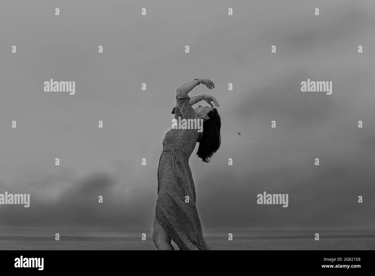 donna in abito lungo che balla sulla spiaggia Foto Stock
