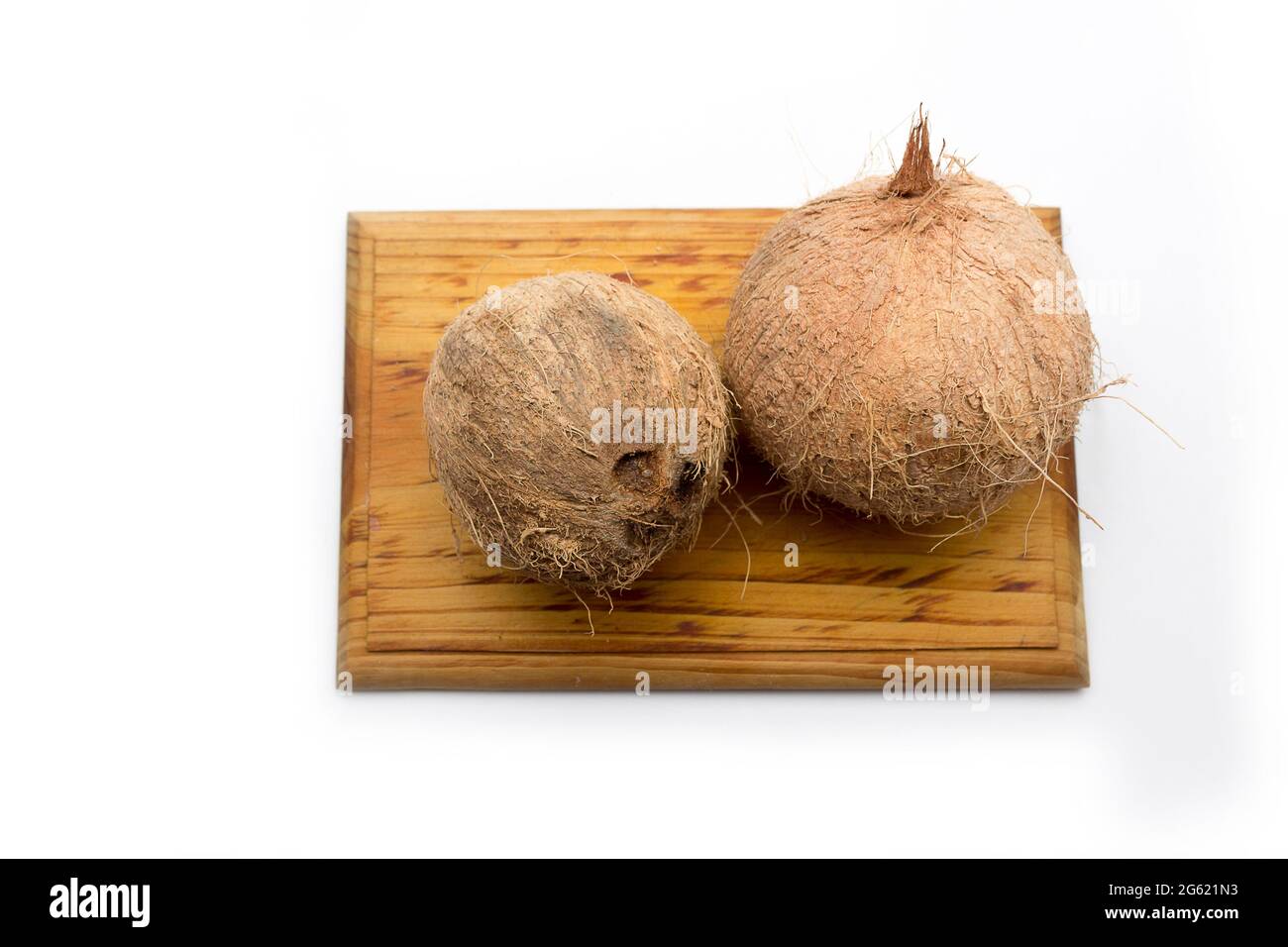 Noci di cocco intere su una tavola di legno su sfondo bianco. Frutta tropicale delle coste caraibiche Foto Stock