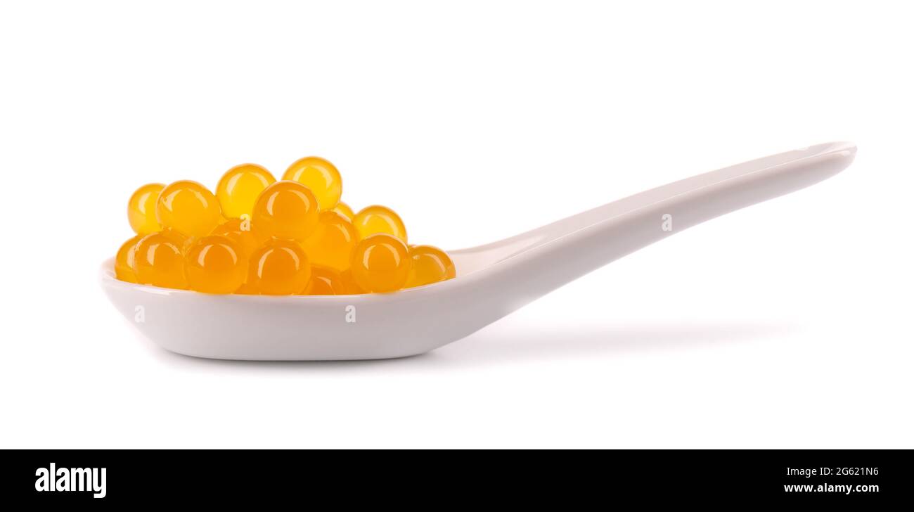 Perle di tapioca gialle per il tè delle bolle isolate su sfondo bianco. Perle di tapioca in cucchiaio di ceramica. Foto Stock