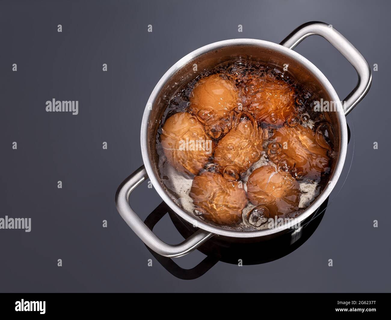 Le uova di pollo bollono in una padella su un piano di cottura in vetroceramica. Cucinando uova sode in una pentola di metallo su stufa elettrica. Far rosolare le uova di guscio in una pentola. Foto Stock