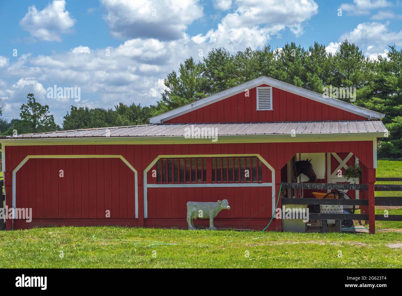 Foto di un fienile rosso nella campagna della Virginia che mostra una statua di un cavallo fuori dal fienile e un vero cavallo all'interno. Foto Stock