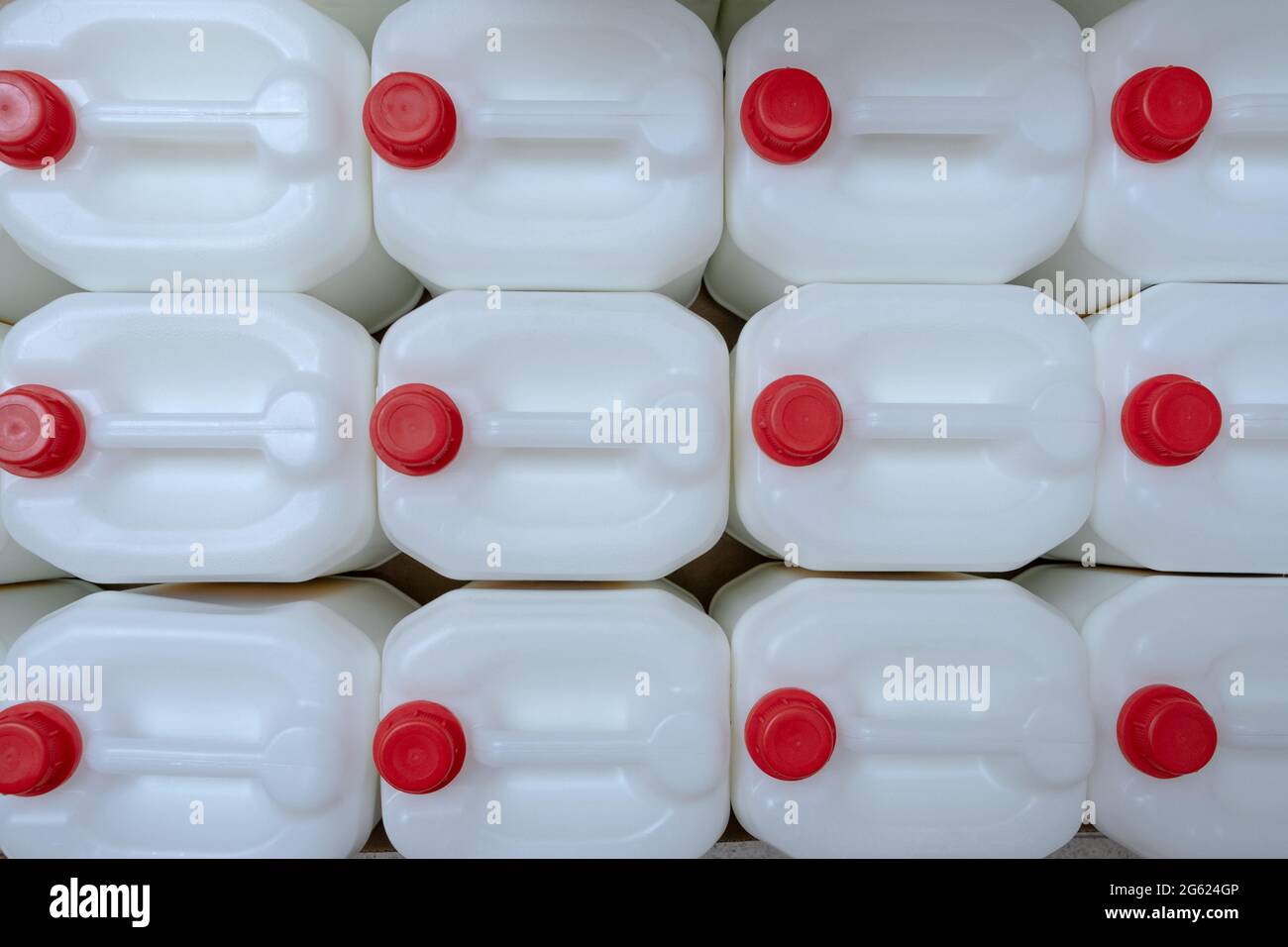 Una fila di bottiglie di ricarica liquidi può contenere prodotti chimici professionali per uso domestico nel magazzino di hardware. Contenitori in plastica bianca con sughero in plastica rossa c Foto Stock