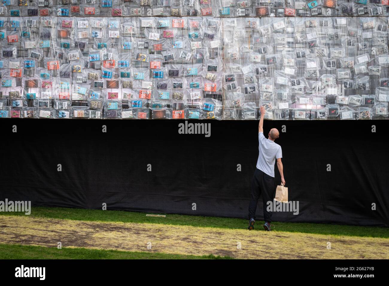 Manchester, Regno Unito. 01 luglio 2021. Il MIF ritorna in città. Un visitatore guarda un libro sul lato del Big ben sdraiato installazione che è creato dal artistÊMarta Minuj'n. La replica di 42 metri del Big ben è coperta in 20,000 copie di libri che hanno plasmato la politica britannica e sono un invito gioioso per le persone a riimmaginare i loro simboli nazionali e unirsi intorno alla democrazia e all'uguaglianza. Il MIF è un festival organizzato da artisti che presenta nuove opere di varie arti dello spettacolo, arti visive e cultura popolare. Credit: Andy Barton/Alamy Live News Foto Stock