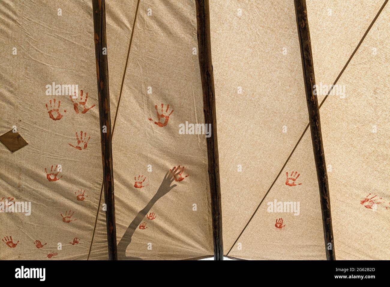 I bambini indigeni delle prime Nazioni mettono le mani dipinte su una teepee per commemorare le tombe non marcate trovate sulla proprietà della scuola residenziale canadese Foto Stock