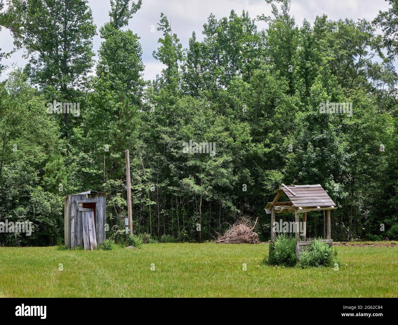 Vecchio outhouse di legno vicino ad un pozzo coperto nella rurale Alabama, Stati Uniti. Foto Stock