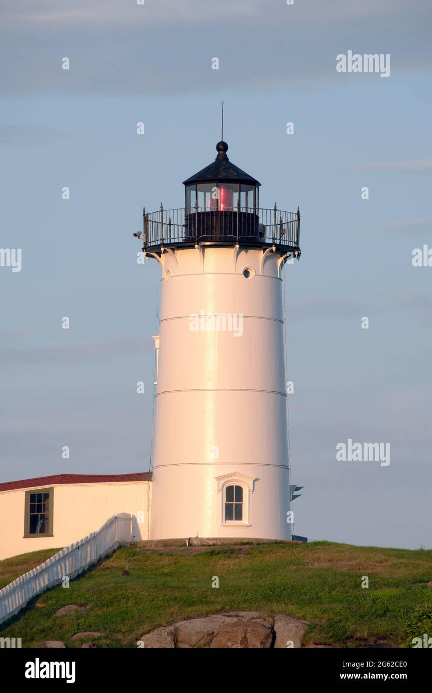 York, Maine, USA, 16 luglio 2019: L'iconico faro di Nubble del Maine si illumina quando il giorno inizia la transizione verso la notte. Foto Stock