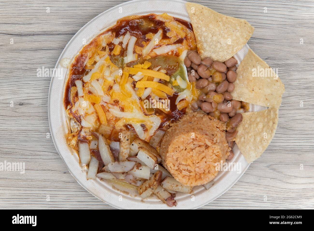Deliziosi rancheros huevos coperti di formaggio, serviti con patate, fagioli e riso per colazione. Foto Stock