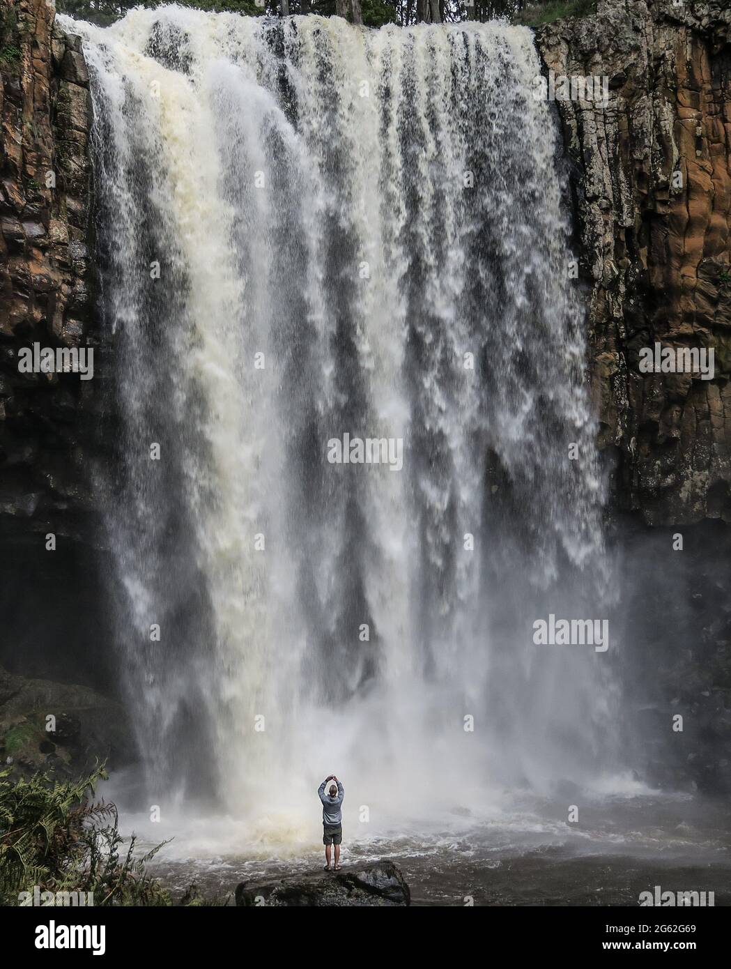 Cascata di Trentham. Le cascate Trentham, appena a nord di Melbourne, Australia, scorrono mentre un turista scatta una foto dal basso. Foto Stock
