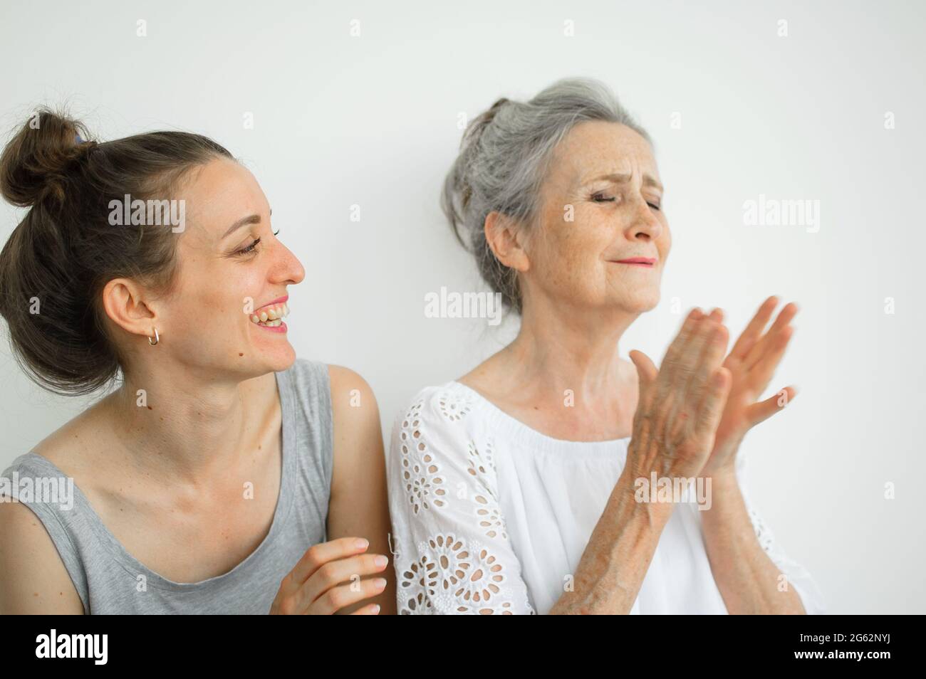Felice madre anziana sta abbracciando la sua figlia adulta, le donne stanno ridendo insieme, famiglia sincera di diverse generazioni di età che si divertono sul bianco Foto Stock