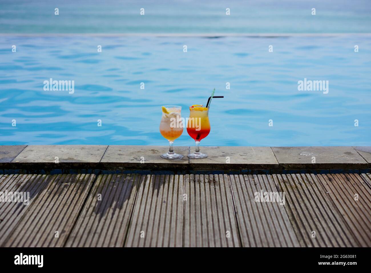 2 bicchieri di cocktail in piscina e sul mare con sfondo bokeh. Concetto di destinazione delle vacanze. Spazio di copia. Nessuna gente. Foto Stock