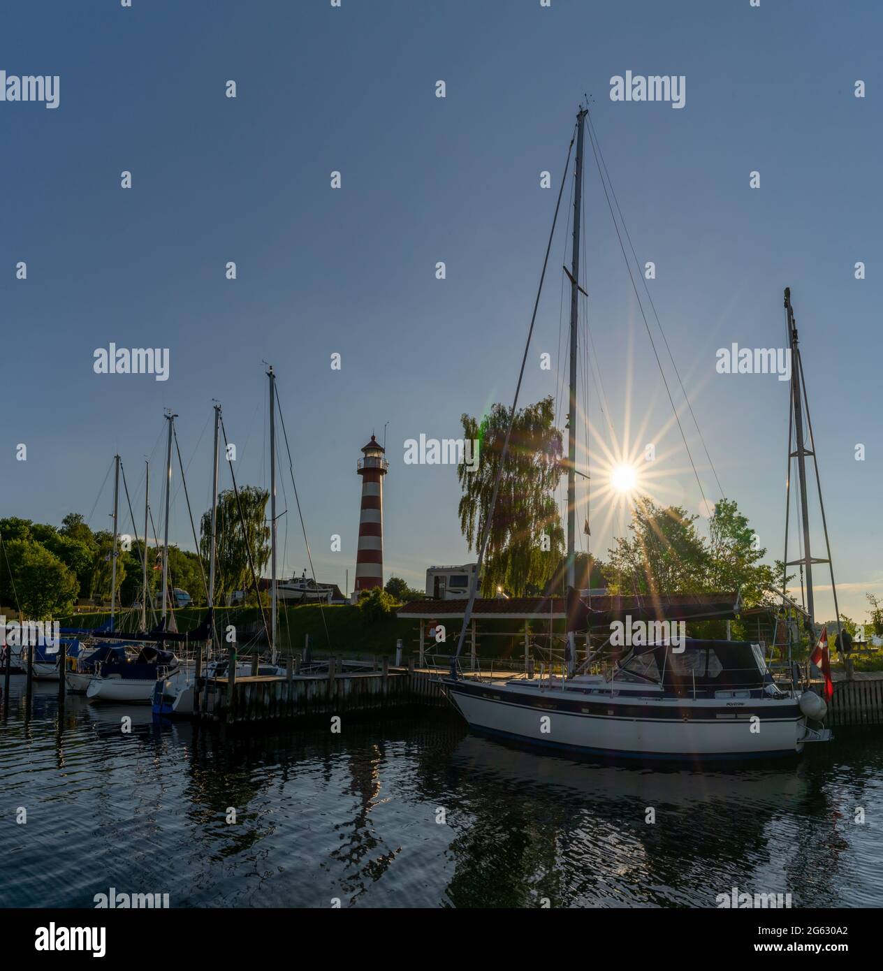 Kongsdal Huse, Danimarca - 7 giugno 2021: barche a vela nel porto di Kongsdal Huve sul fiordo di Mariager con un faro e una stella solare alle spalle Foto Stock
