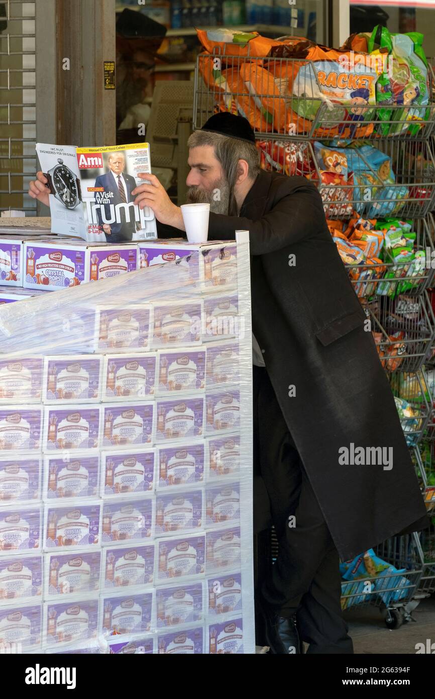 Un ebreo ortodosso legge AMI (ebraico per il mio paese), una rivista per ebrei ortodossi, con una copertina su Donald Trump. A Brooklyn, New York. Foto Stock