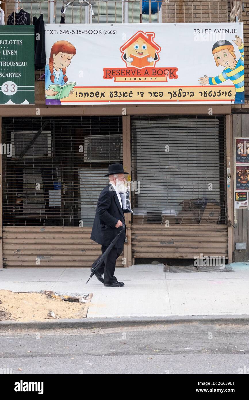 Un ebreo Chassidico cammina presso la Reserve a Book Library su Lee Avenue a Williamsburg, Brooklyn, New York. Foto Stock