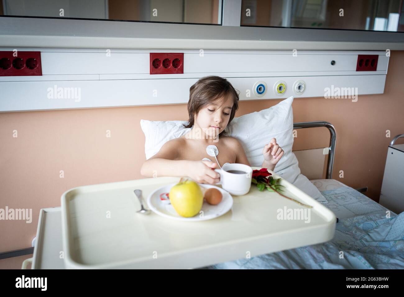 Piccolo ragazzo carino in ospedale a letto al coperto Foto Stock
