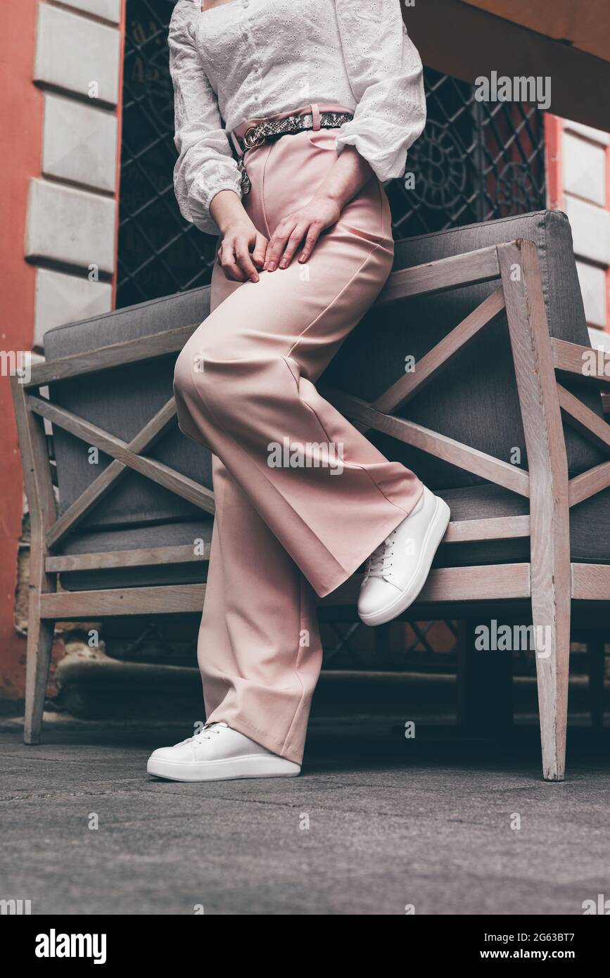 Donna alla moda con scarpe da ginnastica bianche e pantaloni beige, cammina  per la città Foto stock - Alamy