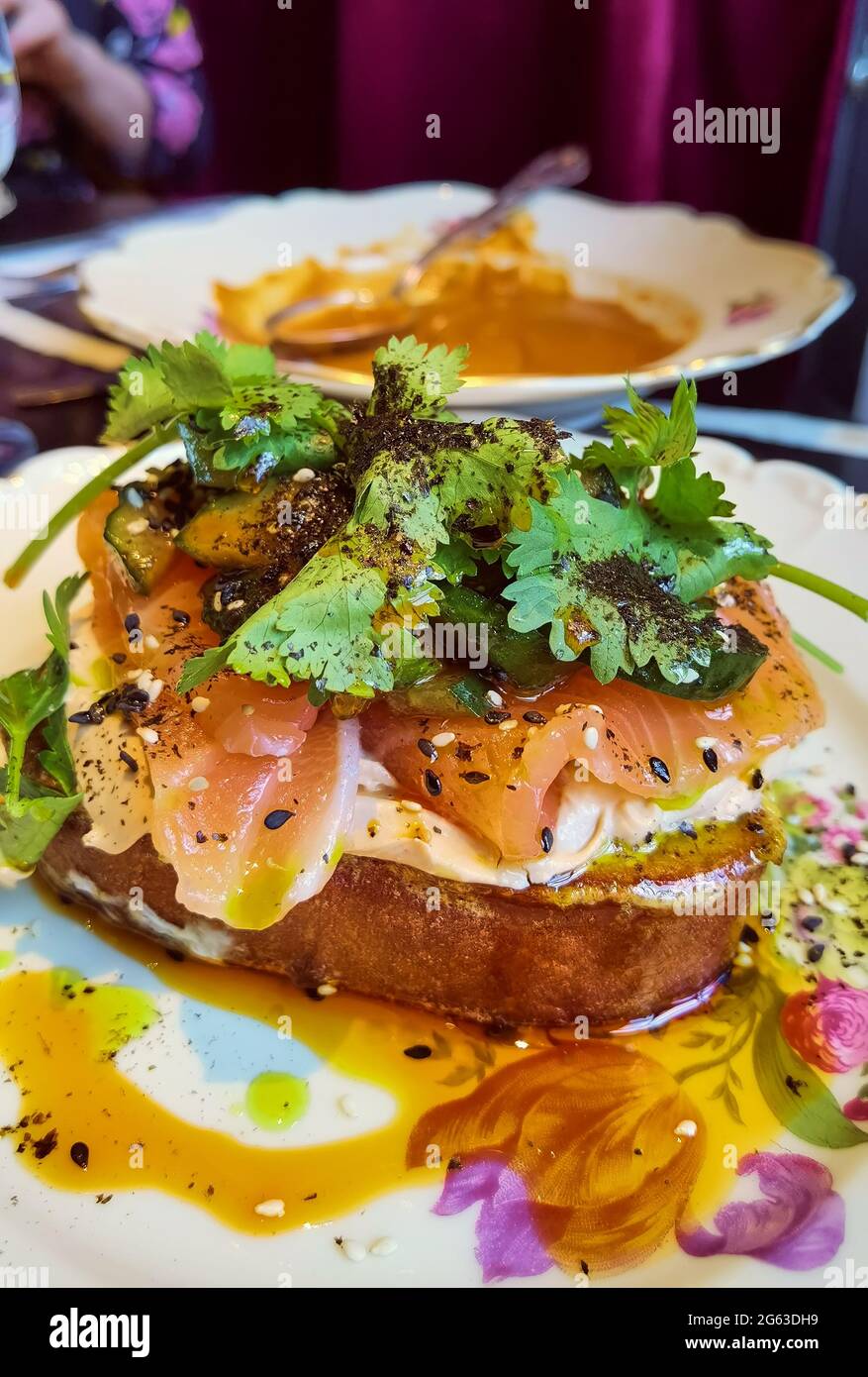 Panino aperto o tartare francese con salmone affumicato, avocado, involtini di zucchine, basilico e erba cipollina tritata su una fetta tostata di pane di pasta acida Foto Stock