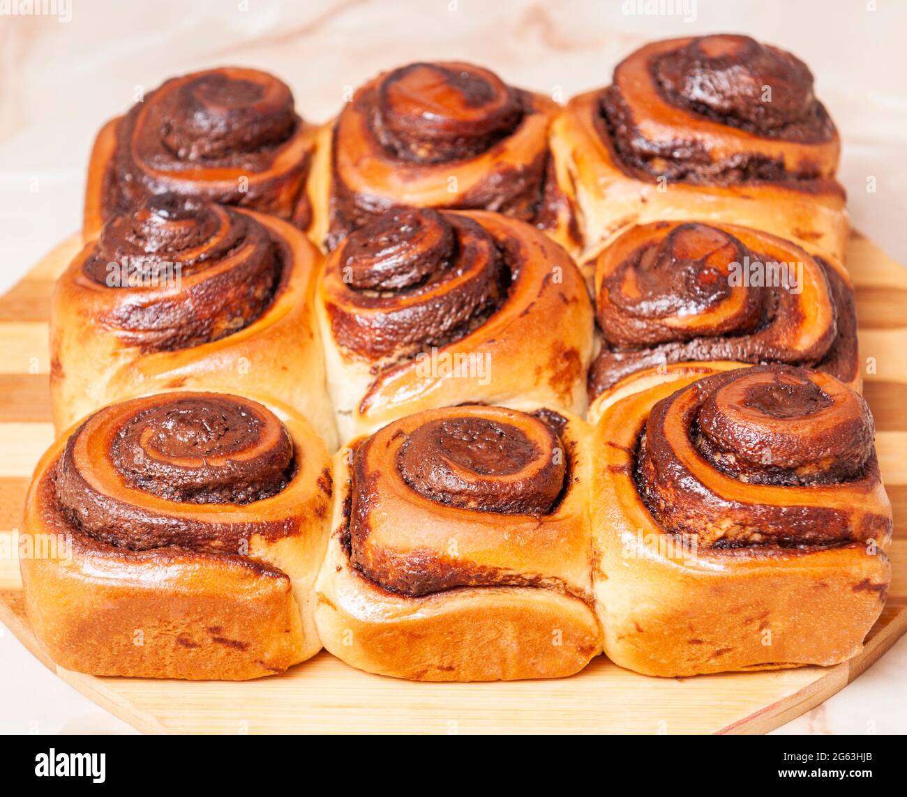 Dolci rotolamenti di cannella su un piatto di legno, foto da angolo Foto Stock