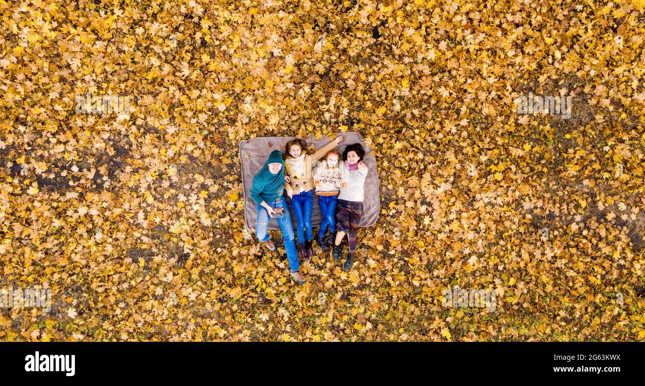 Vista dall'alto sulla famiglia adagiata su foglie gialle Foto Stock