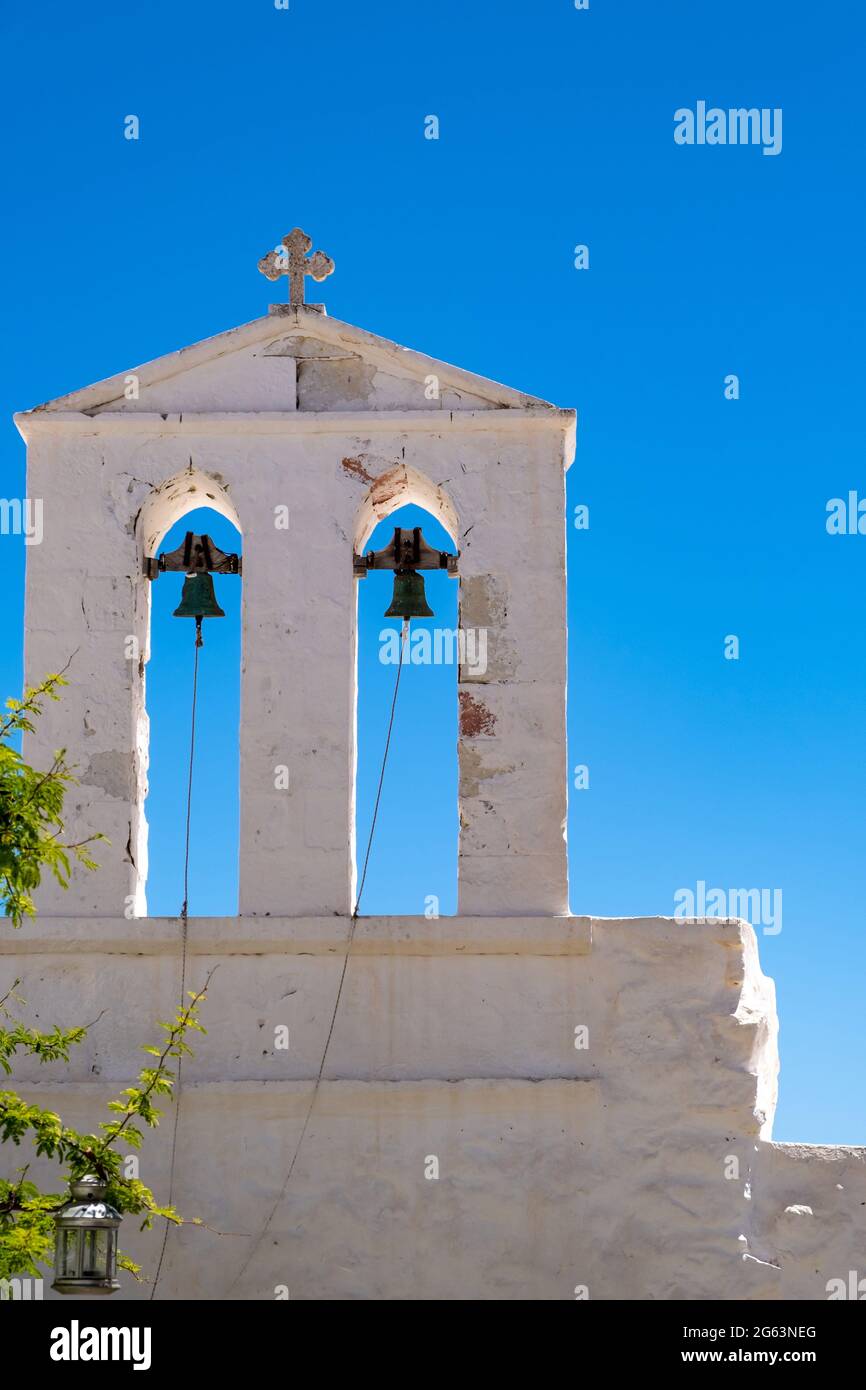 Bianca chiesa ortodossa con croce religiosa su campane torre su chiaro sfondo blu cielo. Isola greca, Cicladi Grecia. Vacanza estiva destinatio Foto Stock