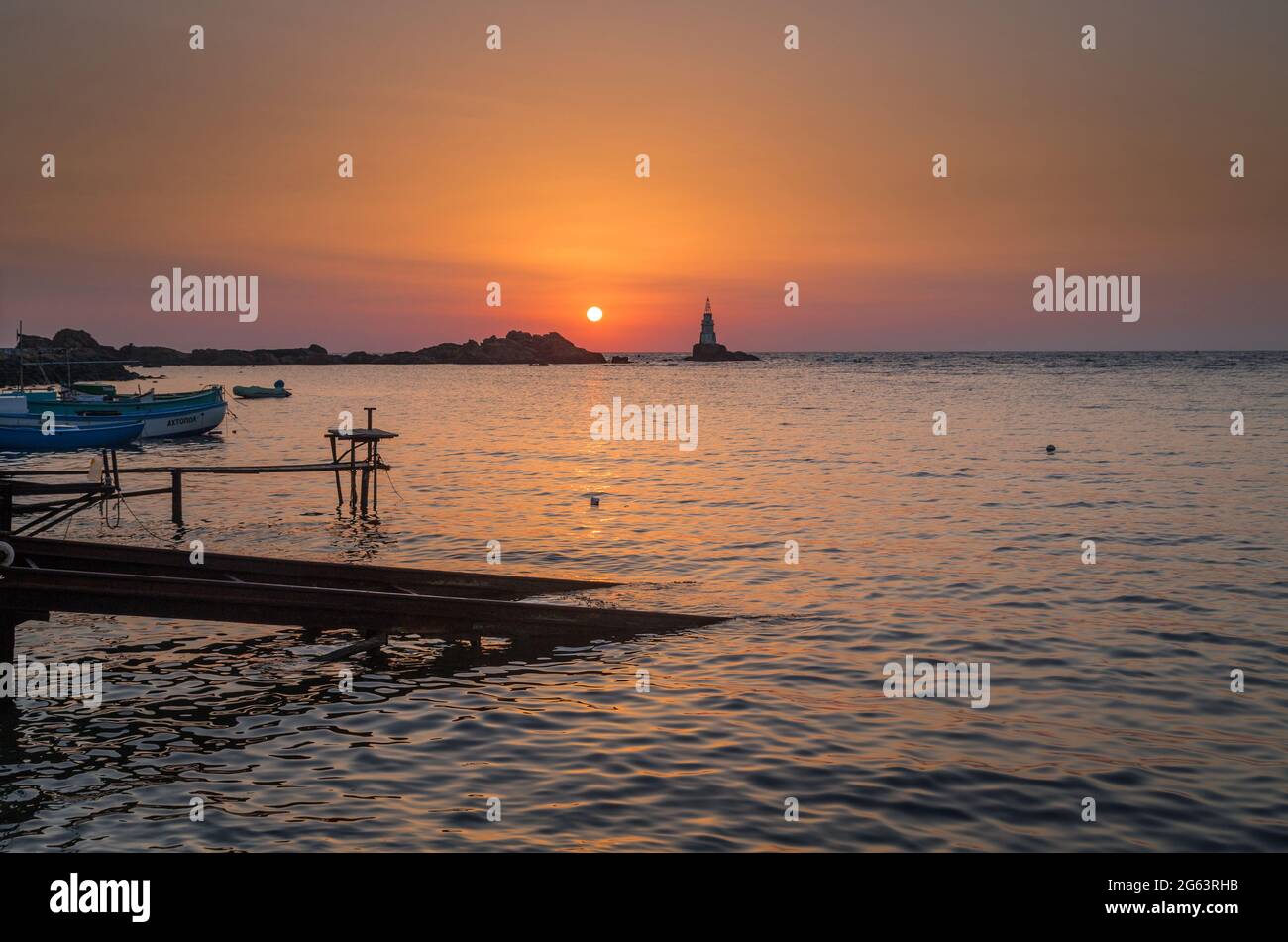 Ahtopol - 10 settembre: Alba sulla spiaggia con molo di pesca, rocce e faro il 10 settembre 2016, Ahtopol, Bulgaria Foto Stock