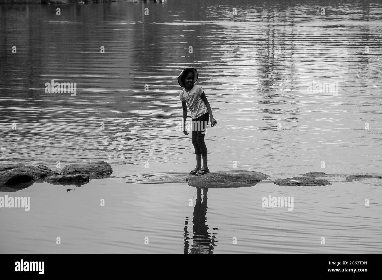 Un bambino cammina lungo la riva del fiume a Sembuwaththa sri lanka. Immagine in bianco e nero Foto Stock